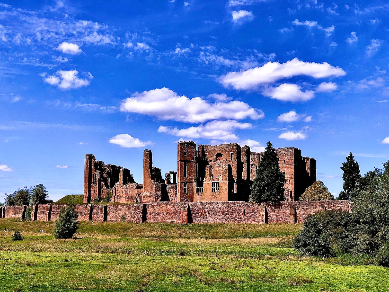 Kenilworth Castle seen across open green fields